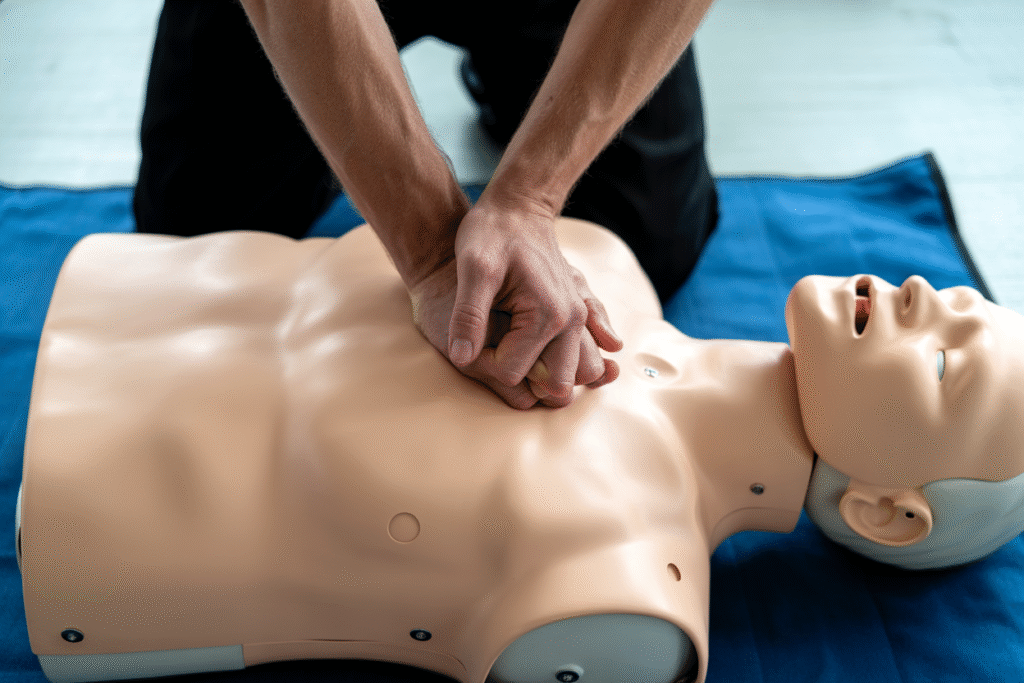 First Aid instructor demonstrating CPR technique on training manikin during practical course session